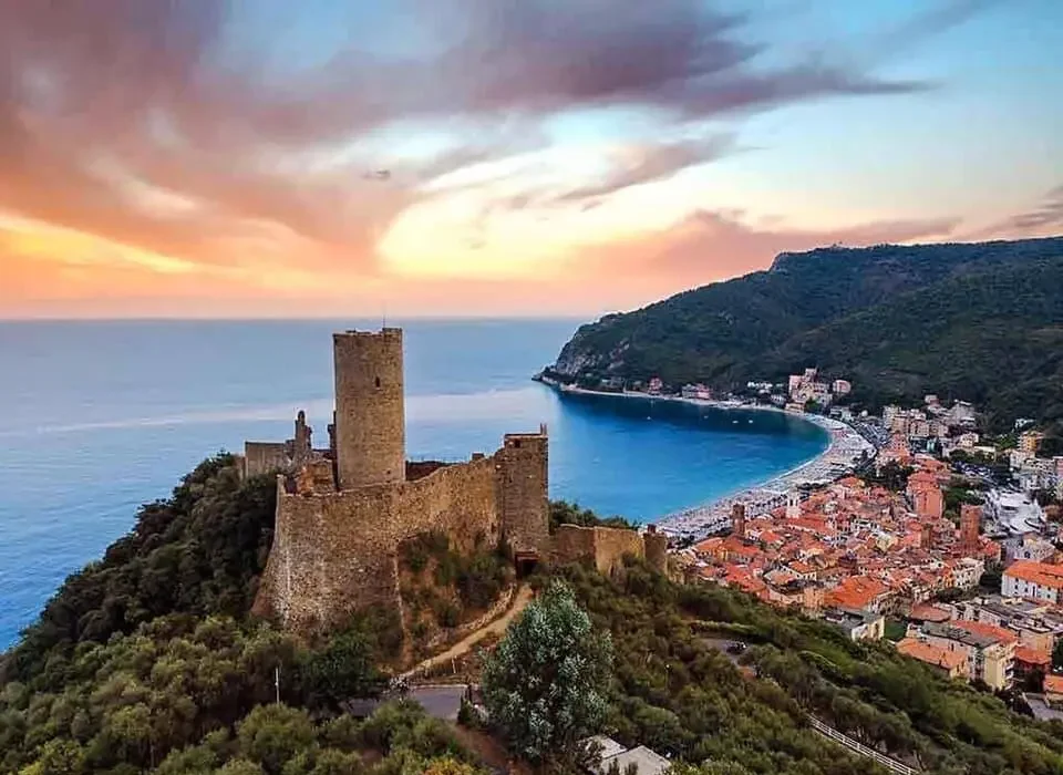 Panorama di Noli con il Castello di Monte Ursino e il golfo al tramonto vicino a Finale Ligure.