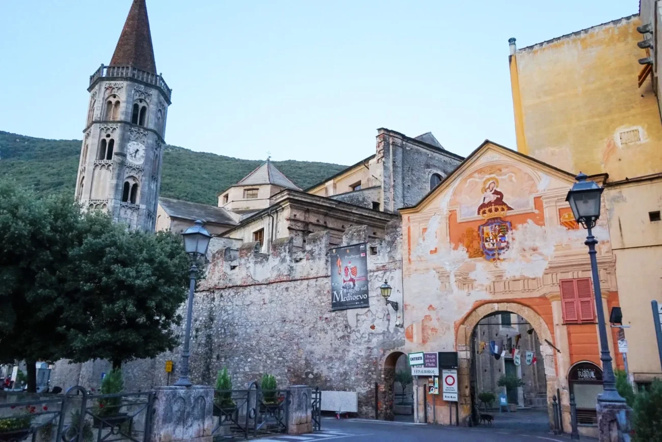 Finalborgo a Finale Ligure con mura medievali, campanile e affresco all’ingresso del borgo.